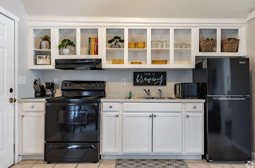a kitchen with white cabinets and black appliances