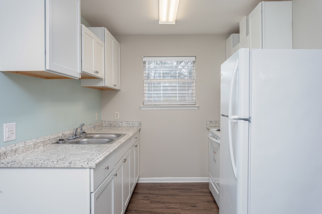 a kitchen with white cabinets and a window