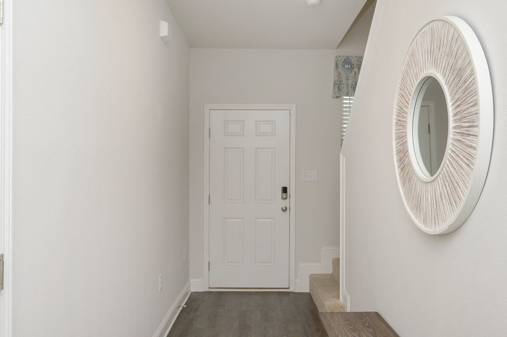 a hallway with a white door and a mirror on the wall