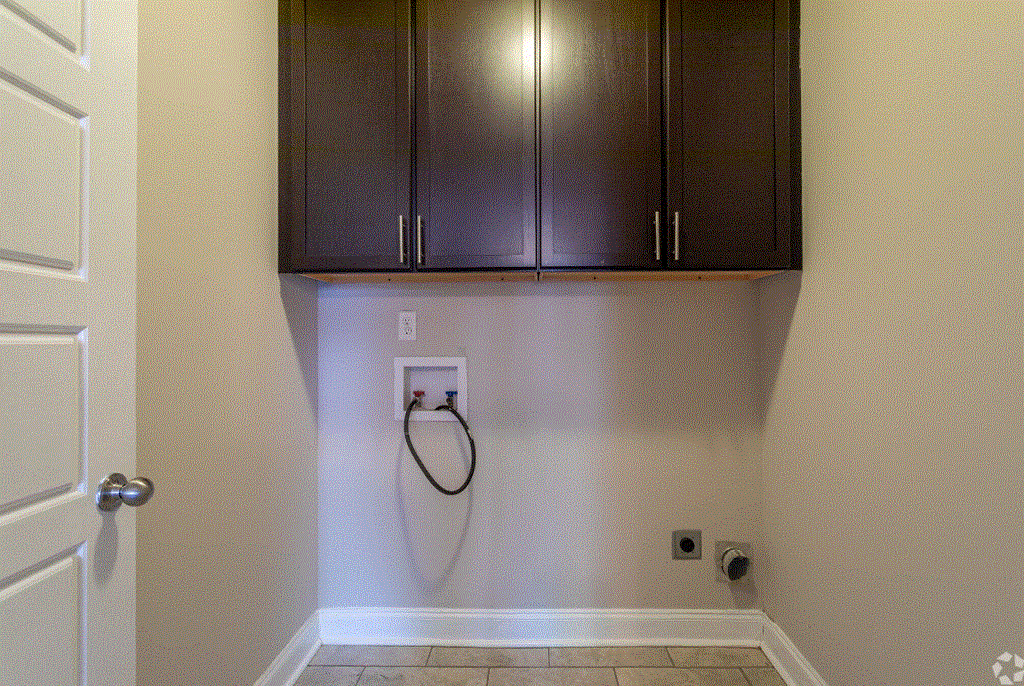 a laundry room with dark cabinets and a white door