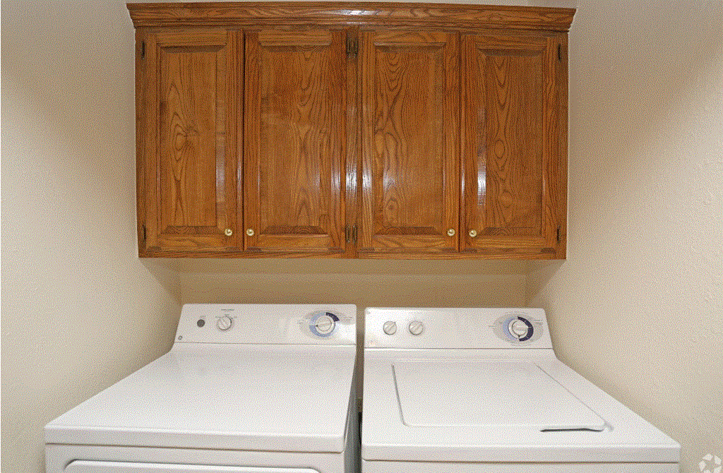 a laundry room with white appliances and wooden cabinets