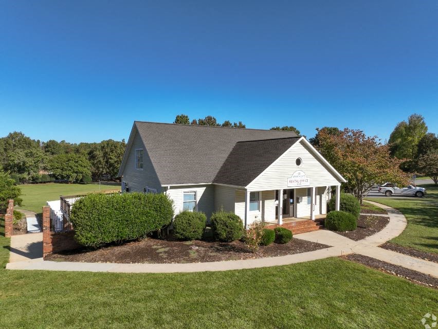 a white house with a gray roof and a green lawn