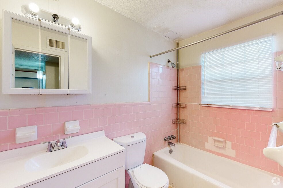 a pink bathroom with a sink toilet and tub