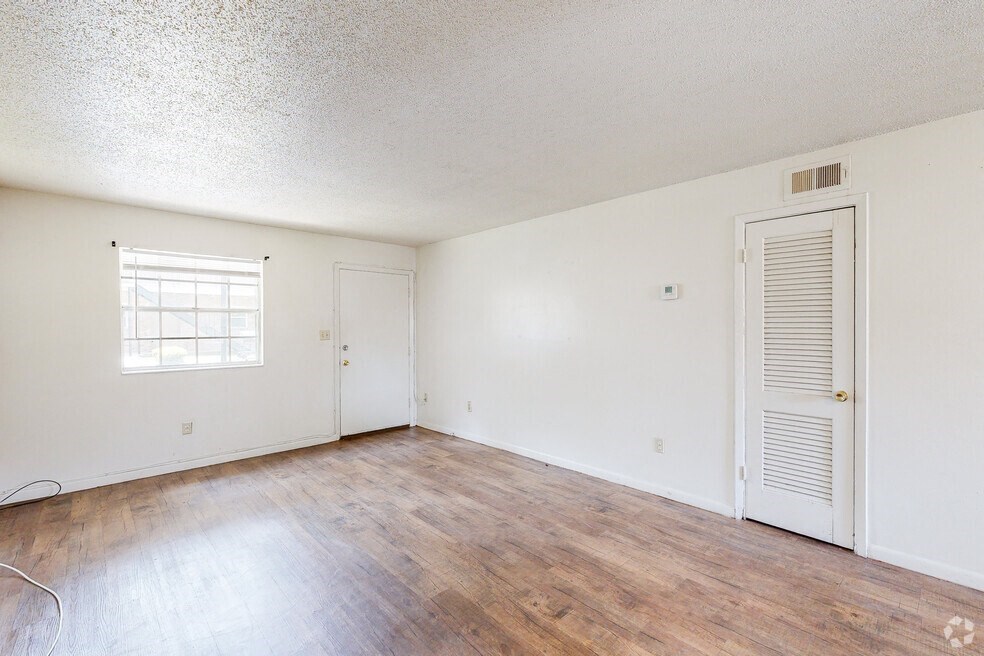 an empty living room with white walls and wood flooring and a white door