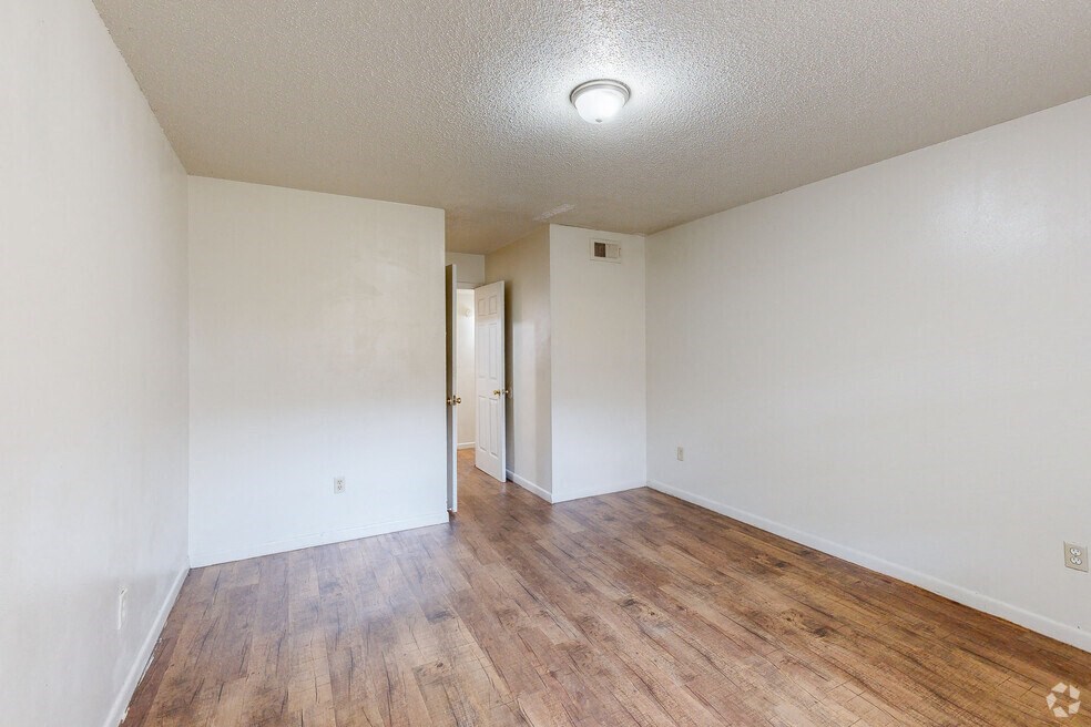 an empty living room with wood flooring and white walls
