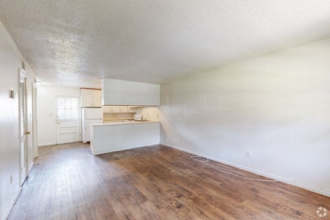 an empty living room and kitchen with wood floors
