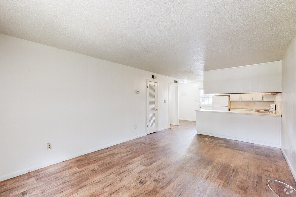the living room and kitchen of an apartment with a wood floor