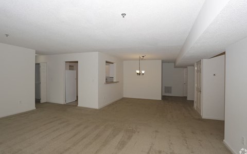 an empty living room and kitchen with white walls and wood floors