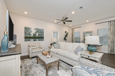 a living room with a white couch and a ceiling fan