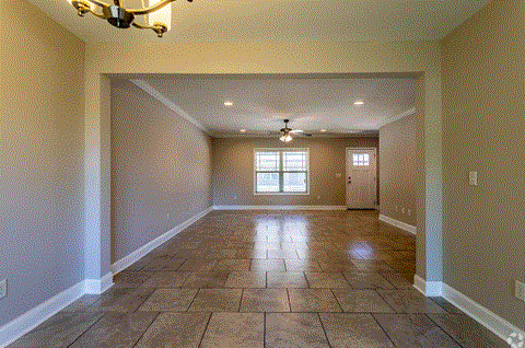 an empty living room with tile flooring and a ceiling fan