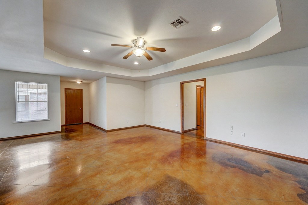 an empty living room with a ceiling fan and a window