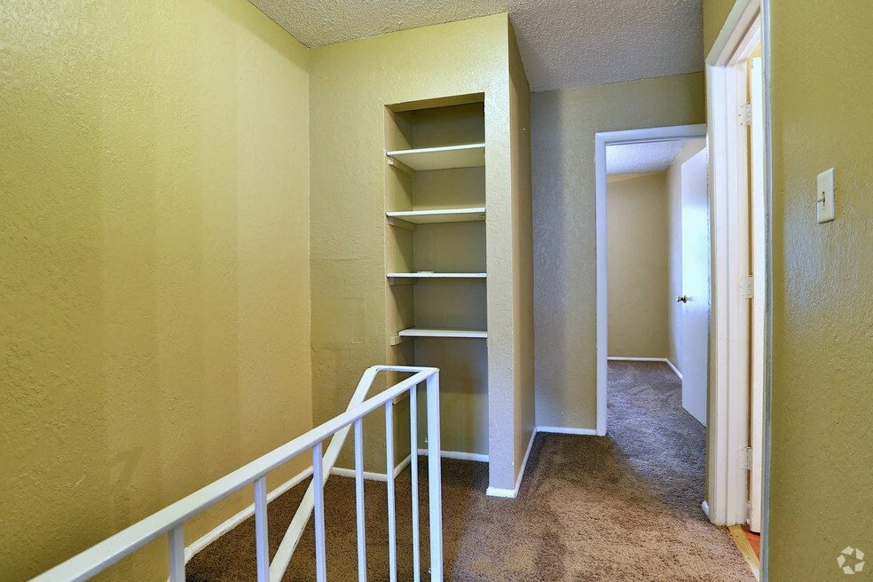 a corridor with a staircase and shelves in a house