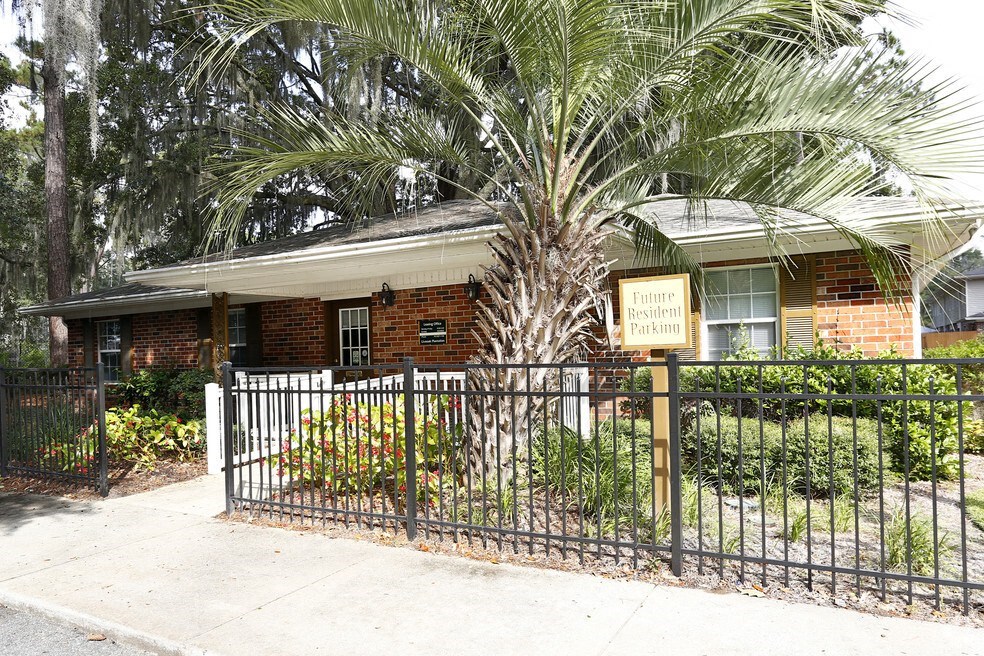a house with a fence and a palm tree in front of it