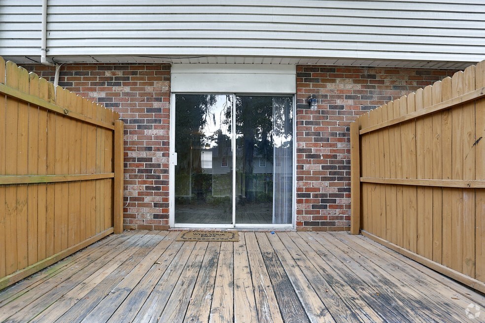 the deck of a brick house with a sliding glass door
