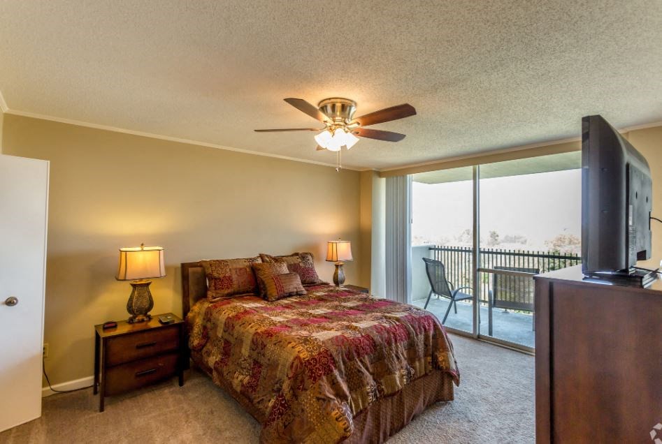 a bedroom with a bed and a ceiling fan and a tv