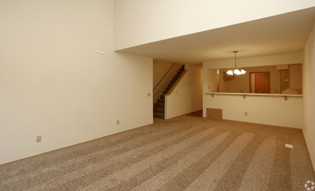 an empty living room with carpet and a staircase