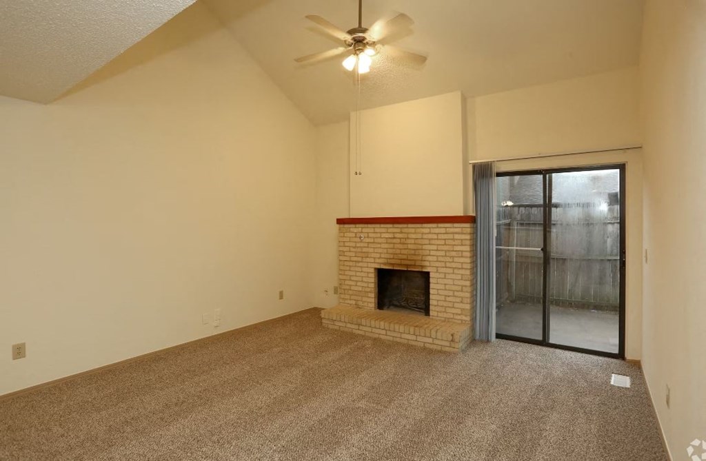 an empty living room with a fireplace and a sliding glass door