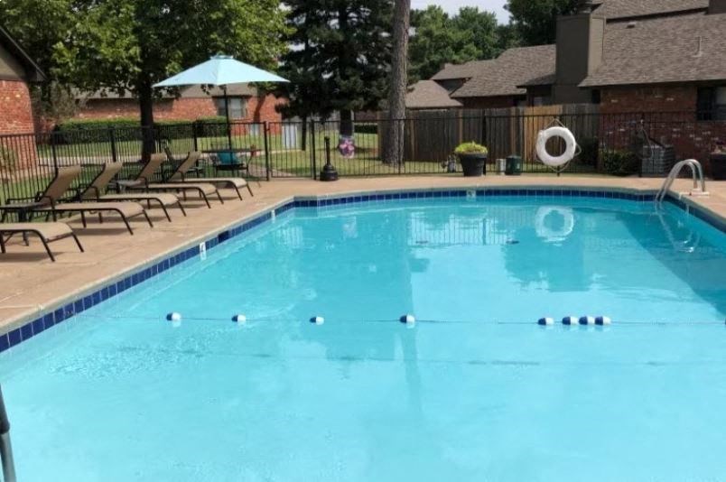 a swimming pool with chairs and a fence around it