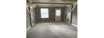 an empty room with a door and two windows