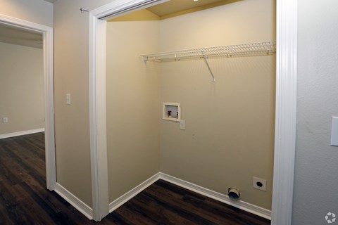 A small closet with a white door and a white shelf.