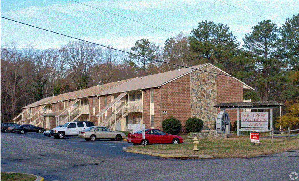 a large brick building with a stone chimney and a parking lot in front of it