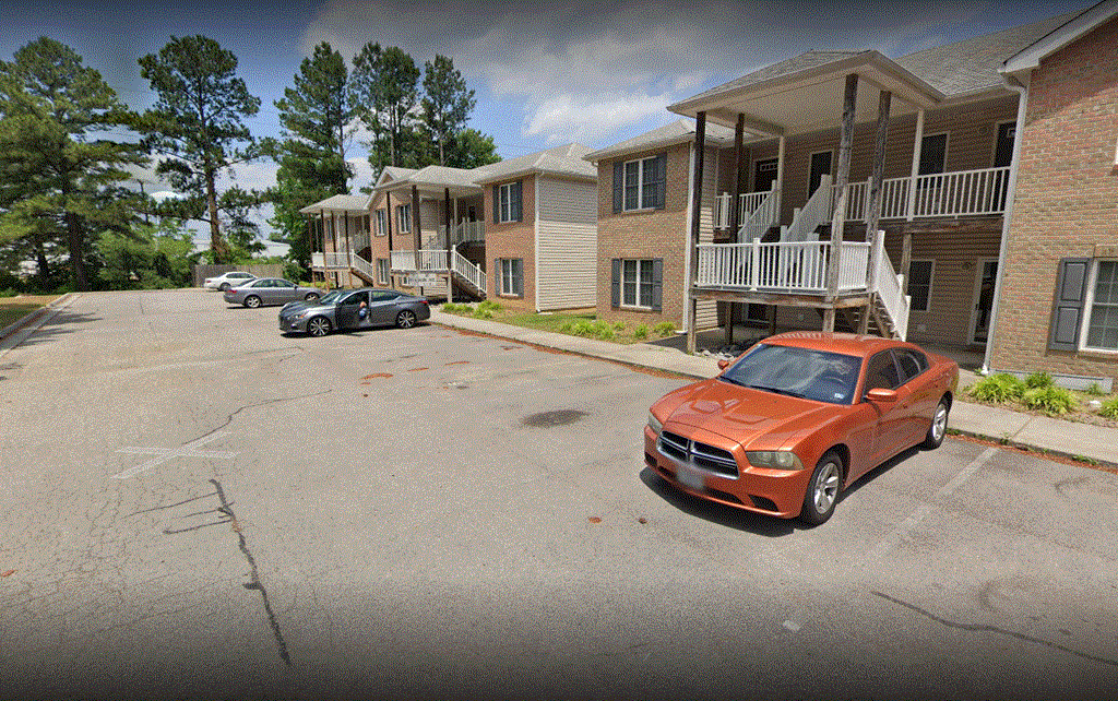 a row of apartment buildings with cars parked in front of them