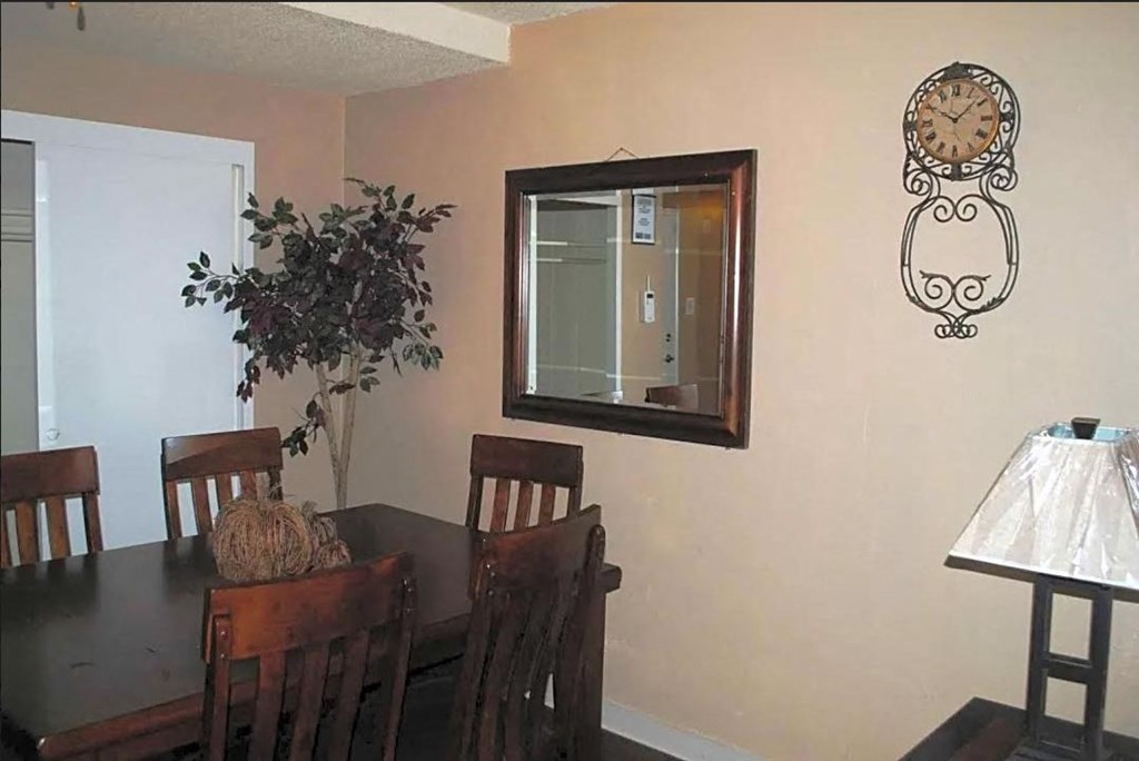a dining room with a table and chairs and a clock on the wall