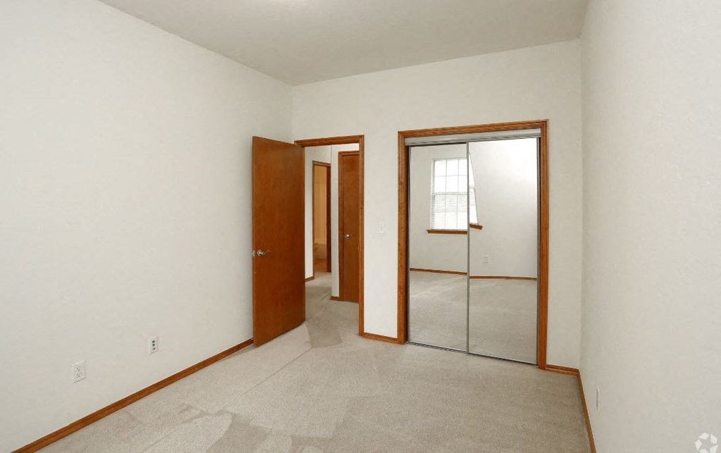 an empty room with a mirror and three doors