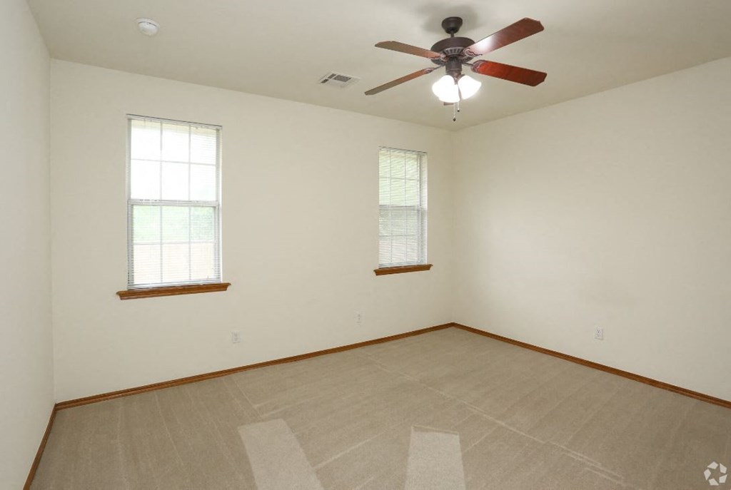 the living room of an empty house with a ceiling fan