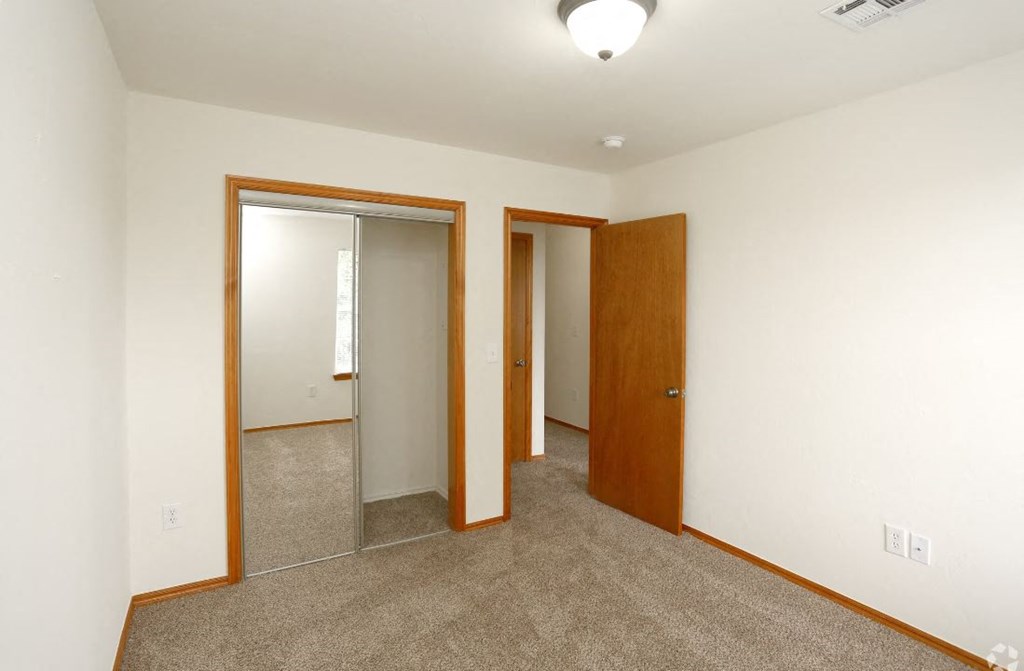 a bedroom with a carpeted floor and a door to a closet