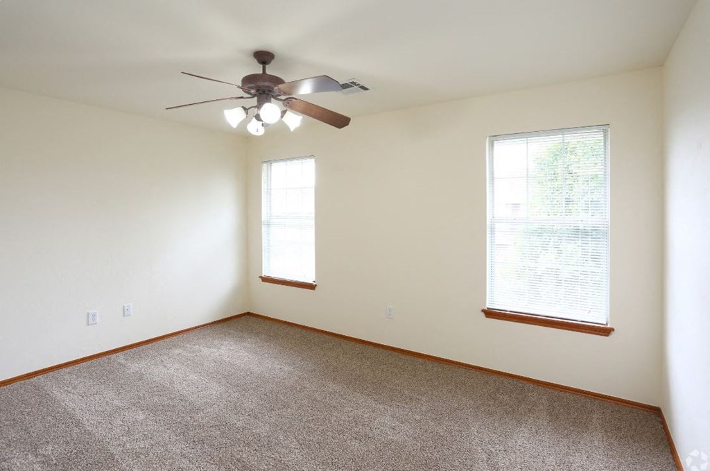 a living room with a ceiling fan and two windows