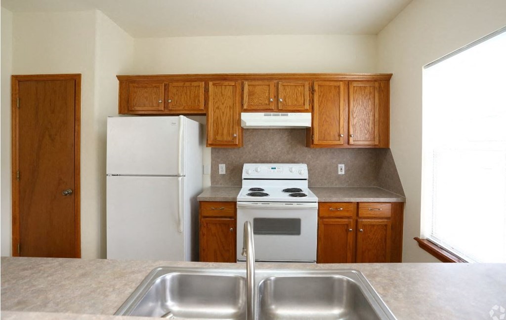 a kitchen with wooden cabinets and a white stove and refrigerator
