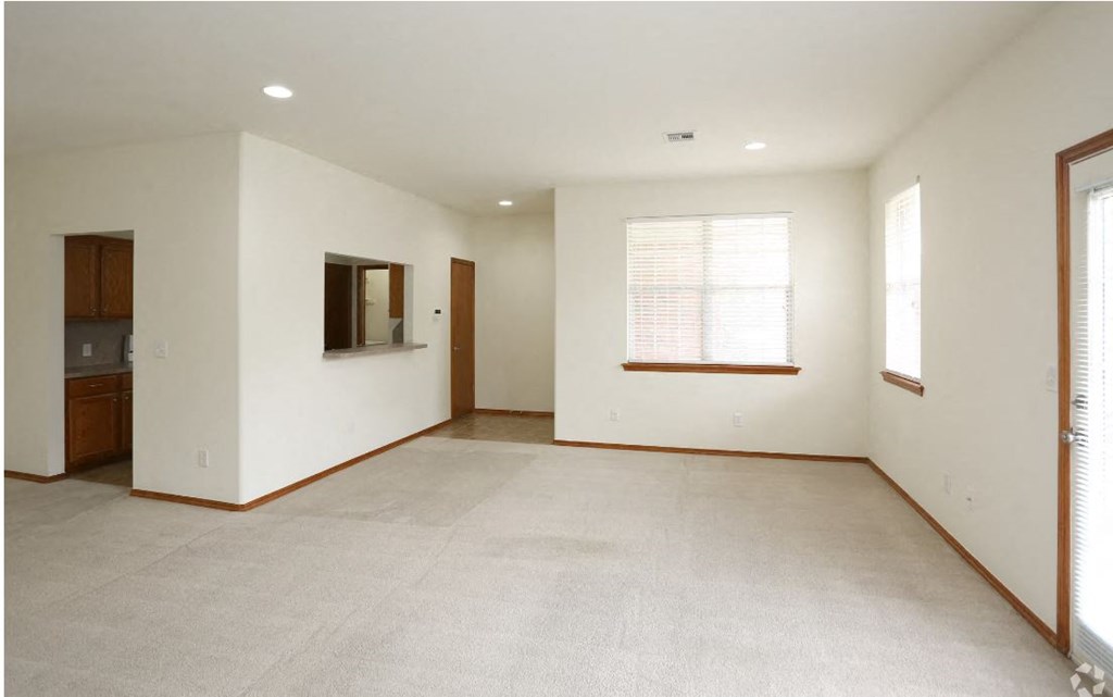 an empty living room with white walls and a window