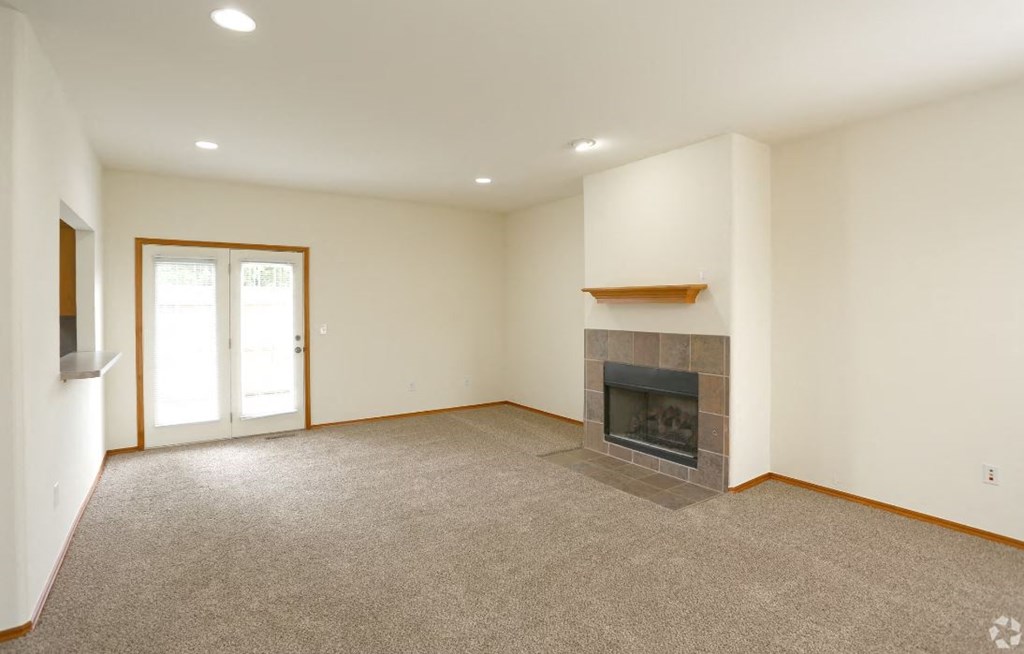 a empty living room with a fireplace and a door