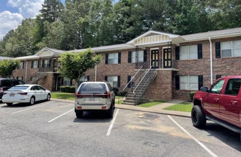 a parking lot with cars in front of a brick apartment building