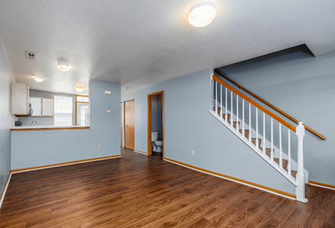 the living room and dining room of a house with blue walls and wood flooring