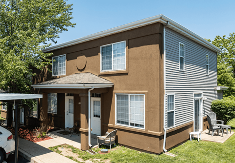 the front of a brown and blue house with a porch