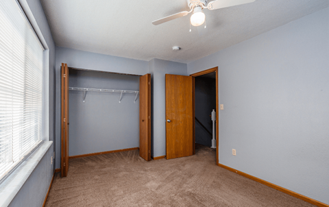a bedroom with a closet and a window and a ceiling fan