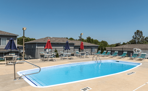 a swimming pool with chairs and umbrellas next to a house