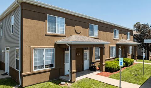 a brown building with a porch and a handicap sign