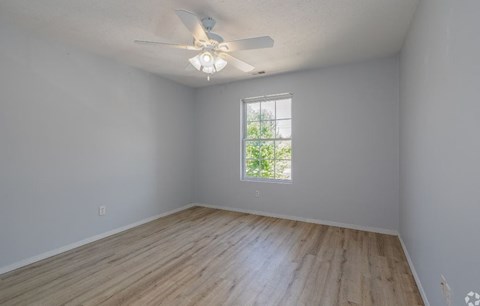 an empty room with a ceiling fan and a window