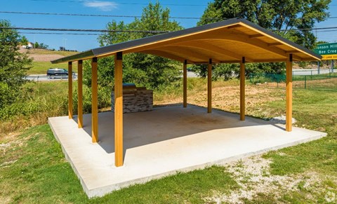 a pavilion with a stone fireplace in the middle of a grassy area