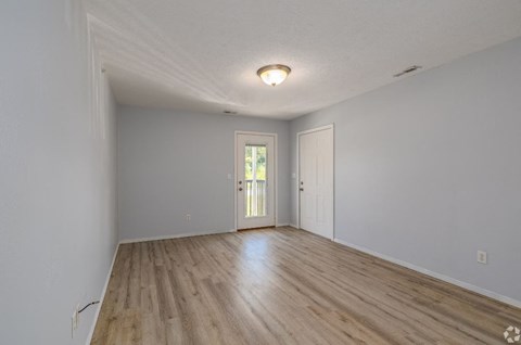 an empty living room with hardwood floors and a door to a patio