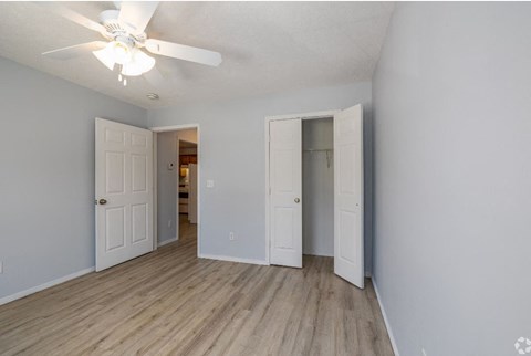 a bedroom with a ceiling fan and a door to a bathroom