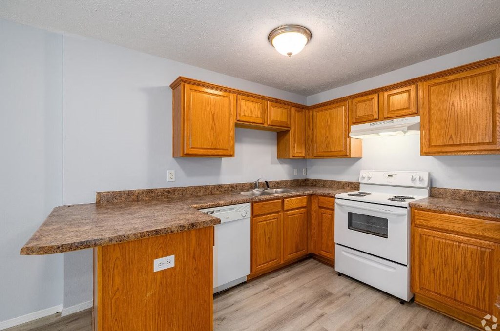 a kitchen with wooden cabinets and a white stove top oven