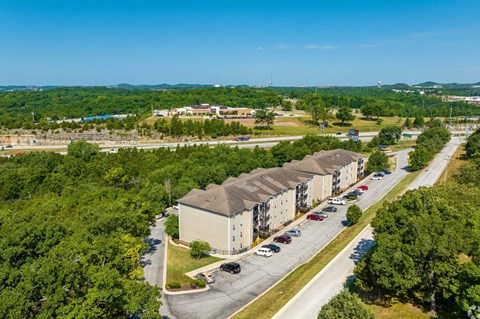 an aerial view of an apartment complex with trees and a blue sky in the background
