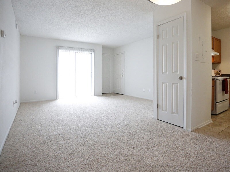 a bedroom with an open door and a kitchen in the background