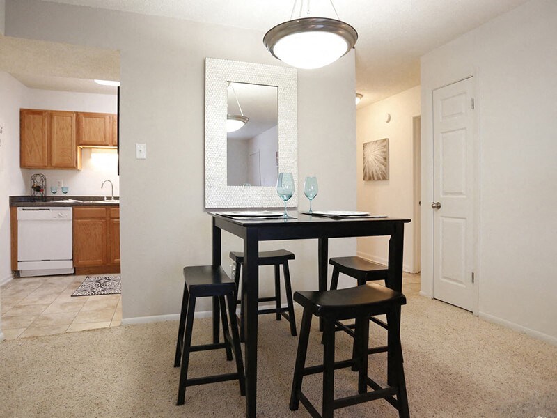 a dining area with a table and chairs and a kitchen in the background