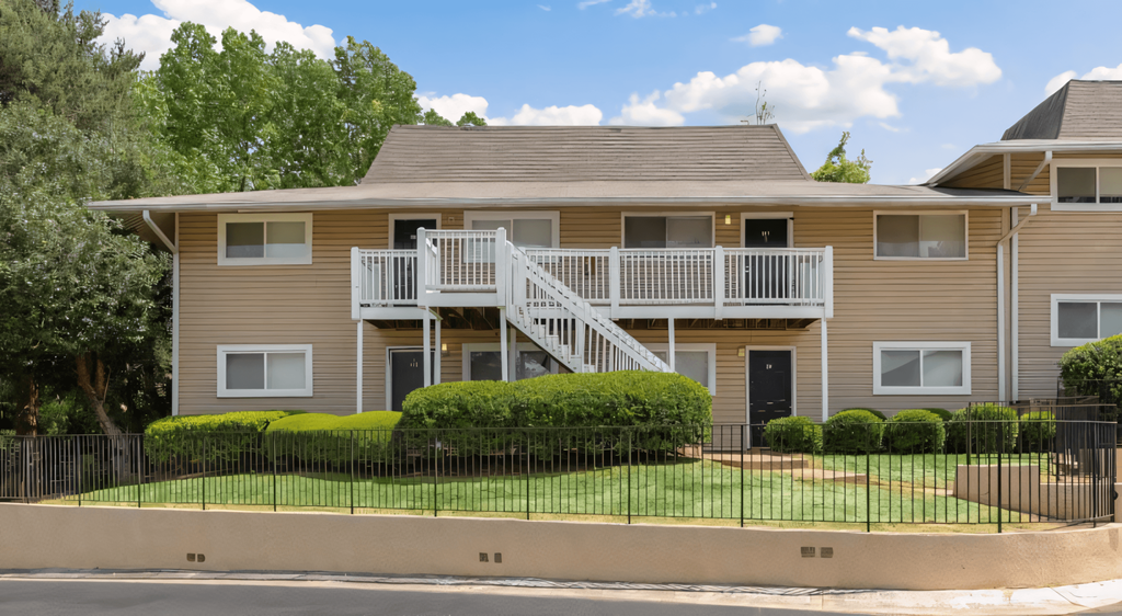 a tan house with a balcony and a black fence