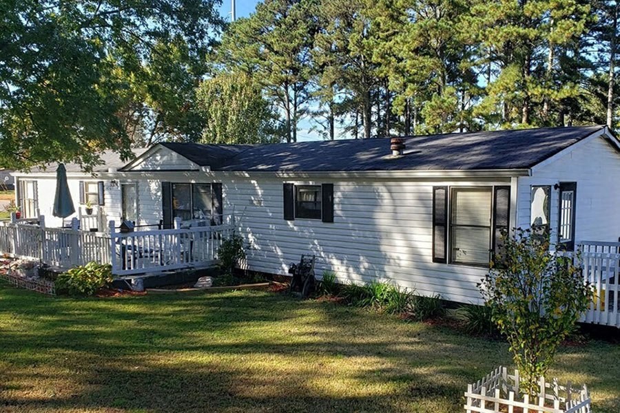 a white house with a black roof and a large yard